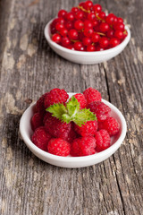 Fresh red currant and sweet raspberries on wooden table