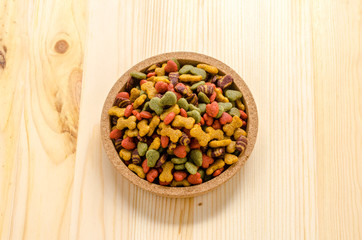Dry dog food in wooden dish and wooden background