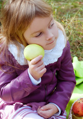 Fototapeta premium Cute little girl in autumn outfit in an apple orchard