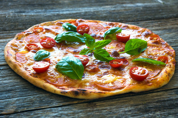 Pizza with mozzarella, tomato and basil leaves