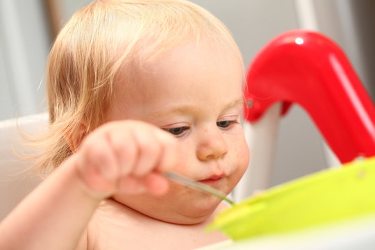 baby eats with a spoon from a plate