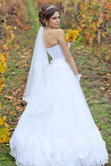 Obraz na płótnie Canvas Beautiful bride in autumn forest with bouquet 