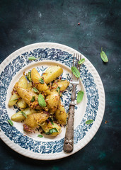 Delicious potatoes with roasted onions and fresh sage leaves. Selective focus