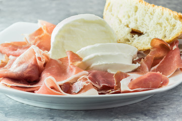 Prosciutto crudo e mozzarella di bufala, con pane nel piatto da portata, antipasto bufala campana