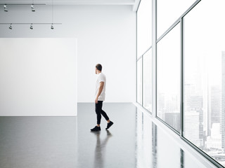 Fototapeta na wymiar Empty gallery interior and walking young man 