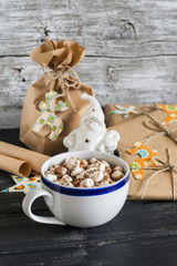 Hot chocolate with marshmallows and homemade Christmas gifts on wooden surface, rustic style