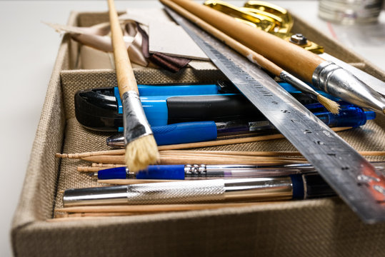 Overhead View Of Hand Tools Placed In Box (aluminum Ruler, Scissors, Wooden Brushes Etc.)