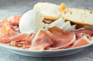 Prosciutto crudo e mozzarella di bufala, con pane nel piatto da portata, antipasto bufala campana