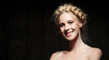 Portrait of a girl with beautiful hairstyle and bare shoulders on a dark background