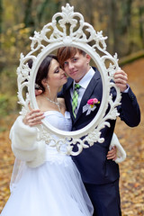 Bride and groom in forest with retro photo frame 