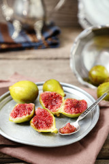 Ripe figs on tray, on wooden background