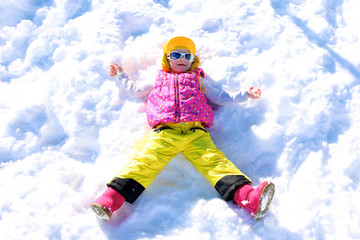 Fototapeta na wymiar Happy child enjoying winter holidays in Alpine resort in Austria. Little girl playing in the snow. Active sportive toddler learning to ski. Kids having fun outdoors.
