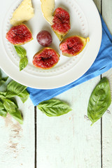 Ripe figs on plate, on color wooden background