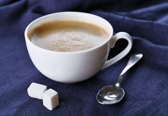 Cup of coffee and sugar on black tablecloth closeup