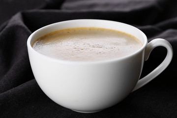 Cup of coffee and sugar on black tablecloth closeup