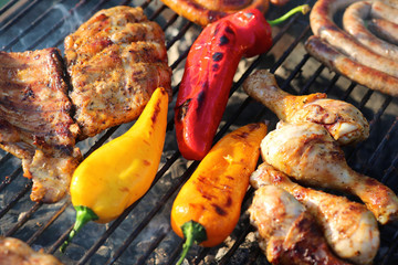 Assorted meat from chicken and pork and colorful sweet paprika on barbecue grill cooked for summer family dinner