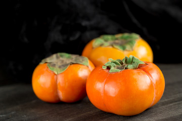 fresh persimmons / fresh persimmons on a dark background