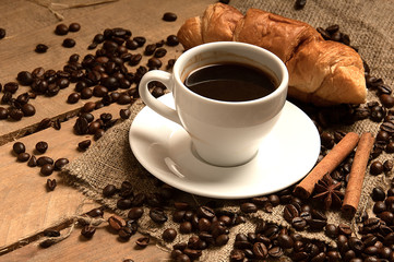 Coffee cup with coffee beans, cigar, cinnamon  on bagging on wood.