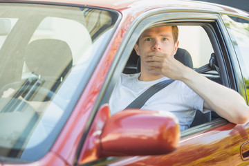 Junger Mann sitzt im Auto und ist schockiert
