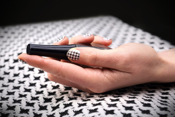 Dłoń kobiety z paznokciami pomalowanymi w czarno biała kratkę