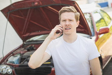 Junger Mann hat Autopanne und telefoniert