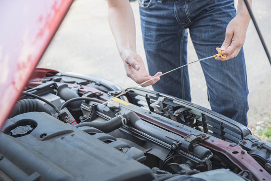 Junger Mann pr&uuml;ft Motor&ouml;l