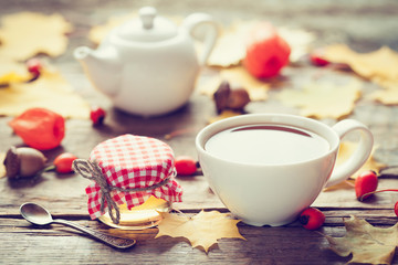 Tea cup, jar of honey and teapot on background. Autumn still lif