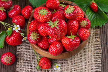organic strawberries with leaves over wooden background