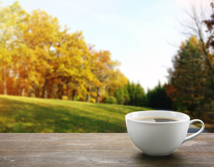 Cup of coffee on table on nature background