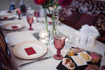 interior of the restaurant,  large table laid for  Banquet, decorated in Burgundy tones
