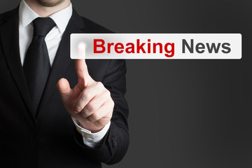 businessman in black suit pushing flat touchscreen button breaking news
