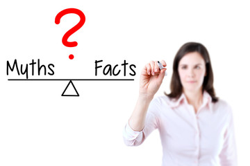 Young business woman writing myths and facts compare on balance bar. Isolated on white background.