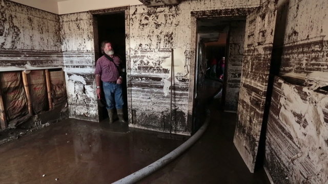 Flood basement man walks through room in mud water P HD 2087