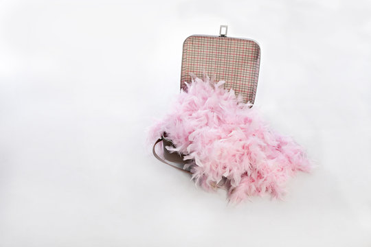 old brown suitcase isolated on a white background overflowing with pink feathers 
