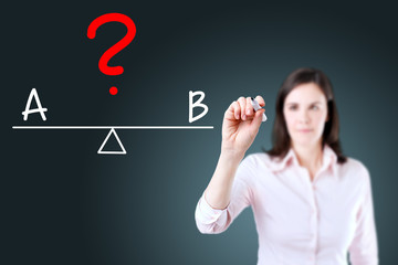 Young business woman writing A and B compare on balance bar. Blue background.