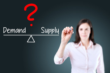 Young business woman writing demand and supply compare on balance bar. Blue background.