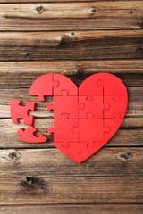 Red puzzle heart on brown wooden background