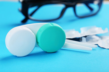 Contact lenses in container with solution on blue background