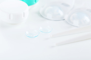 Contact lenses in container with solution on white background
