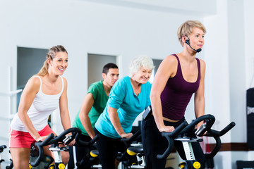 Fototapeta na wymiar Senior people in gym spinning on fitness bike