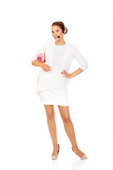 Young businesswoman in headset holding piggybank