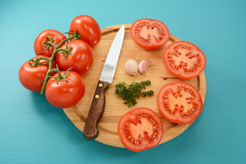 Tomatoes cut for roasting with knife, garlic and thyme
