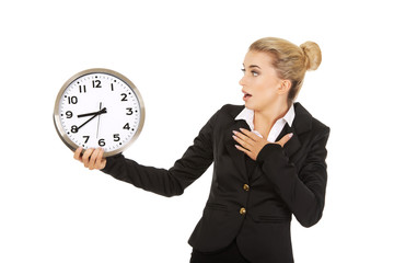 Young businesswoman terrified looks at the clock