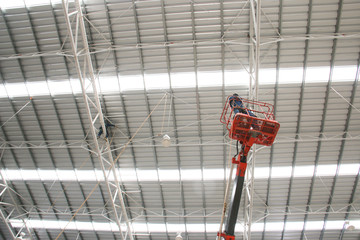 workers on orange boom lift repair roof