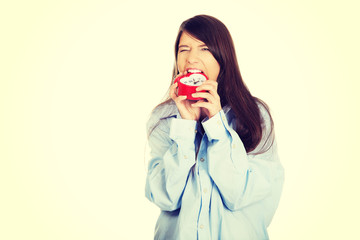 Angry woman in big shirt holding alarm clock.