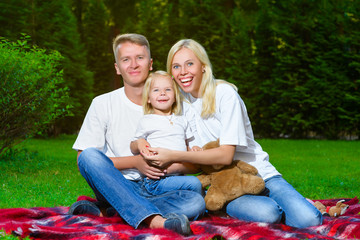 Fototapeta premium Happy family lying on the grass in summer. Picnic concept