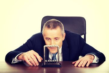 Businessman in office playing with newton balls