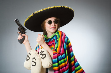 Girl in mexican poncho holding handgun and money sacks against g