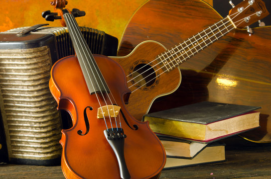 Violin, guitar and books on still-life wooden background