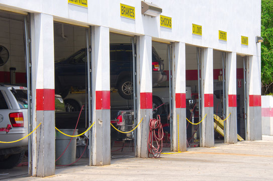 Automobile auto repair garage with open doors showing vehicles on lifts being worked on